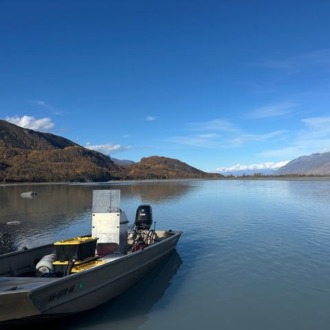 An aluminum Sea Ark jet boat with its 140 hp jet outboard at the edge of a river below fall-colored mountains in Alaska.