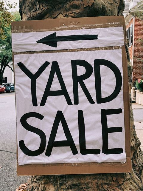 A hand-painted yard sale sign nailed to a tree.